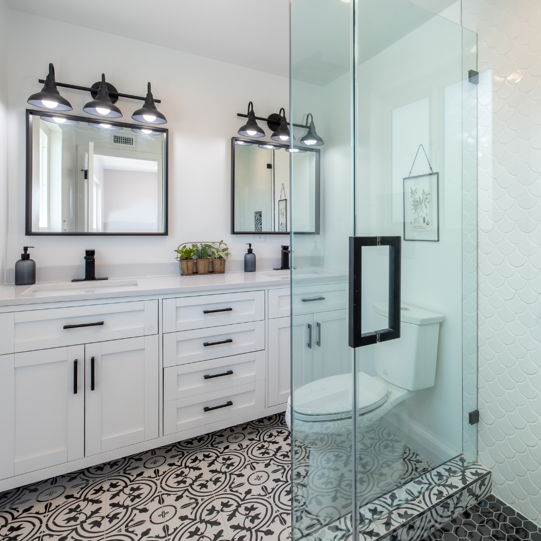 bathroom with bkack and white geometric tile white walls and a double sink