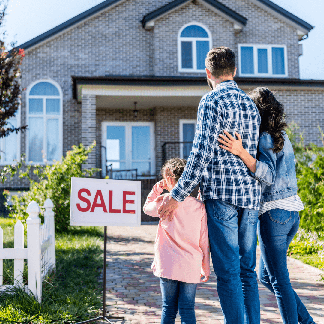 1 a young family stand with their backs to the camera as they look at a house for sale